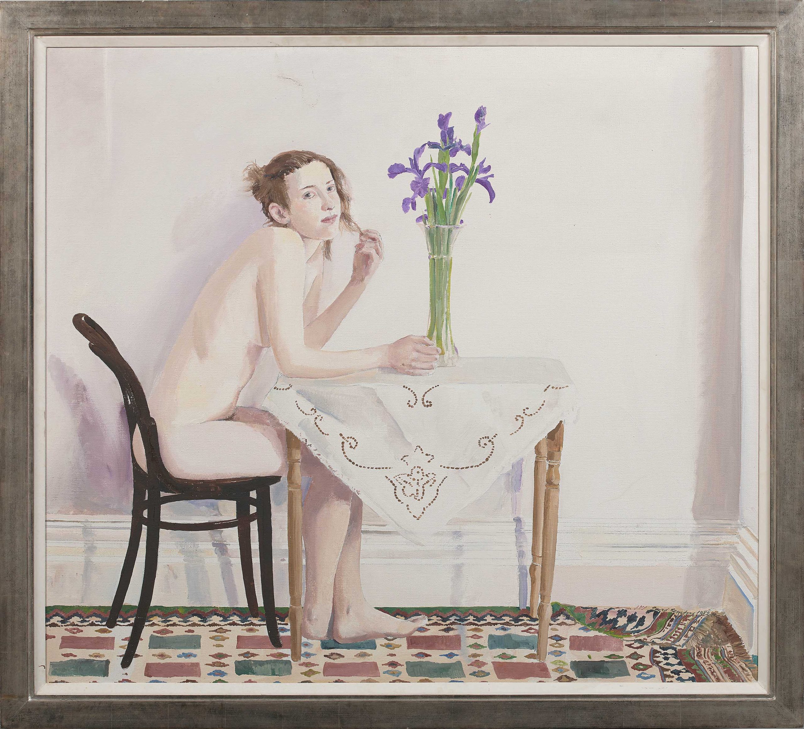 Nude Lady sitting at a tableclothed table with flower in a vase